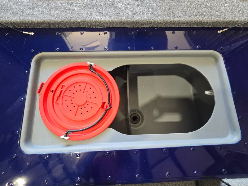 Slide: The Image of 2025 G3 Sportsman 1710 boat compartment with red lid, open storage area. - 8