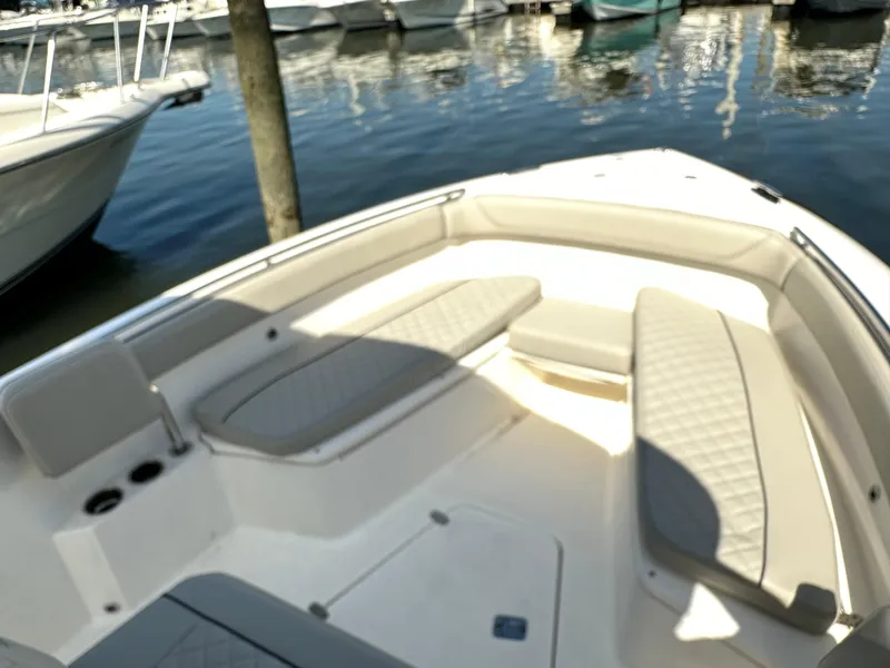 Slide: The Image of 2024 Pursuit S 268 Sport boat interior with cushioned seating at marina. - 7