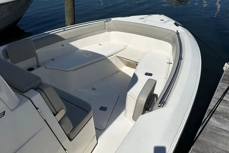 Slide: The Image of 2024 Pursuit S 268 Sport boat interior with seating and storage, docked on calm water. - 9