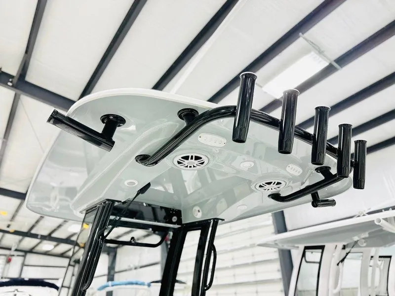 Slide: The Image of 2025 Sportsman Open 232 boat T-top with rod holders in a warehouse. - 7