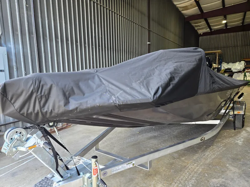Slide: The Image of 2025 G3 Sportsman 1810 PFX boat covered in a protective tarp, stored indoors. - 4