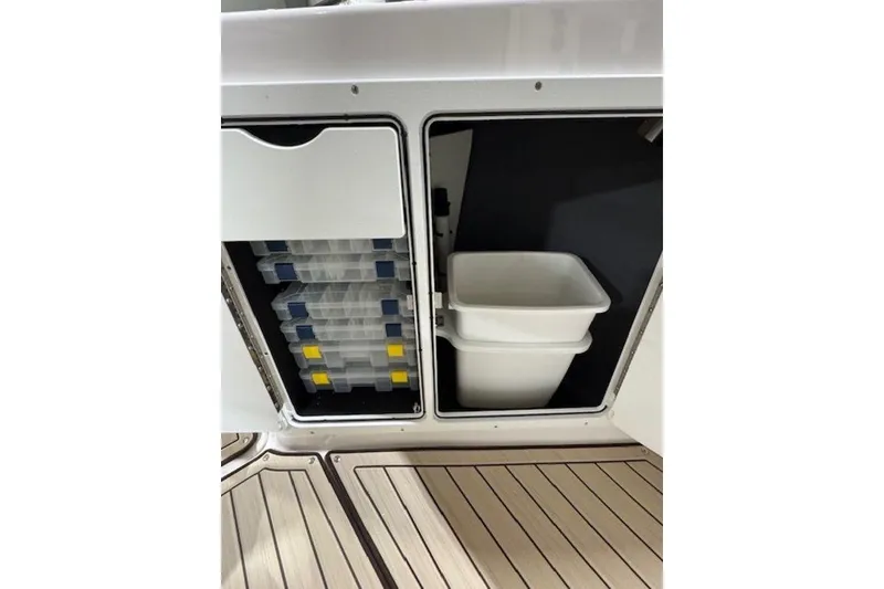 Slide: The Image of Storage compartments on 2025 Yamaha Boats 252 FSH Sport, featuring tackle boxes and bins. - 12