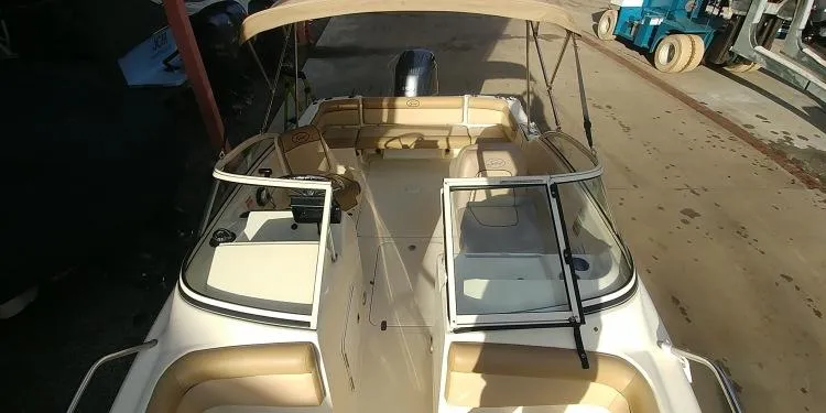 Slide: The Image of 2013 Scout 210 Dorado boat with beige seating and canopy, docked in a marina. - 18
