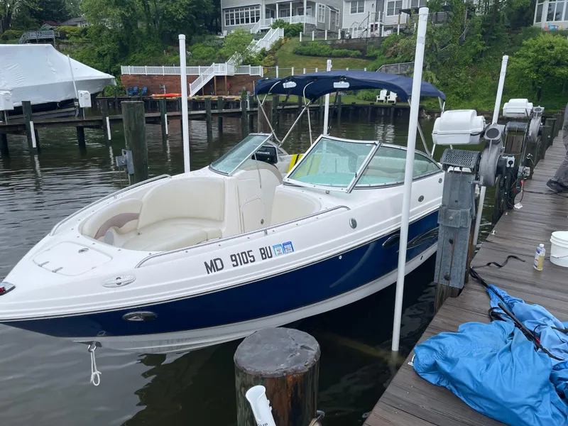The Image of 2005 Chaparral Sunesta 236 boat docked by a wooden pier, featuring a blue and white design. - 0