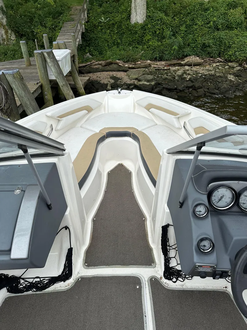 Slide: The Image of 2012 Chaparral 220 SSi boat interior with dashboard and seating, docked by lush greenery. - 11