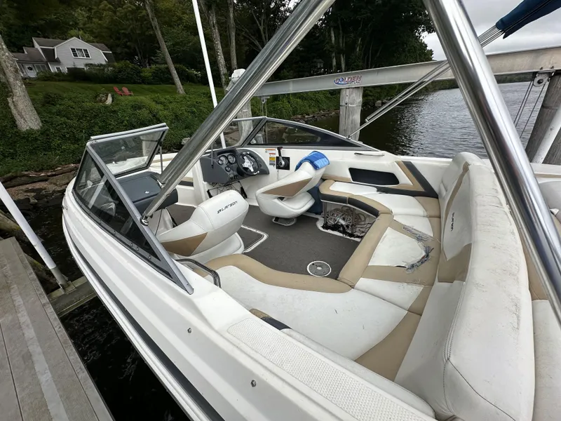 Slide: The Image of 2012 Chaparral 220 SSi boat interior with seating and steering wheel, docked by a lake. - 3