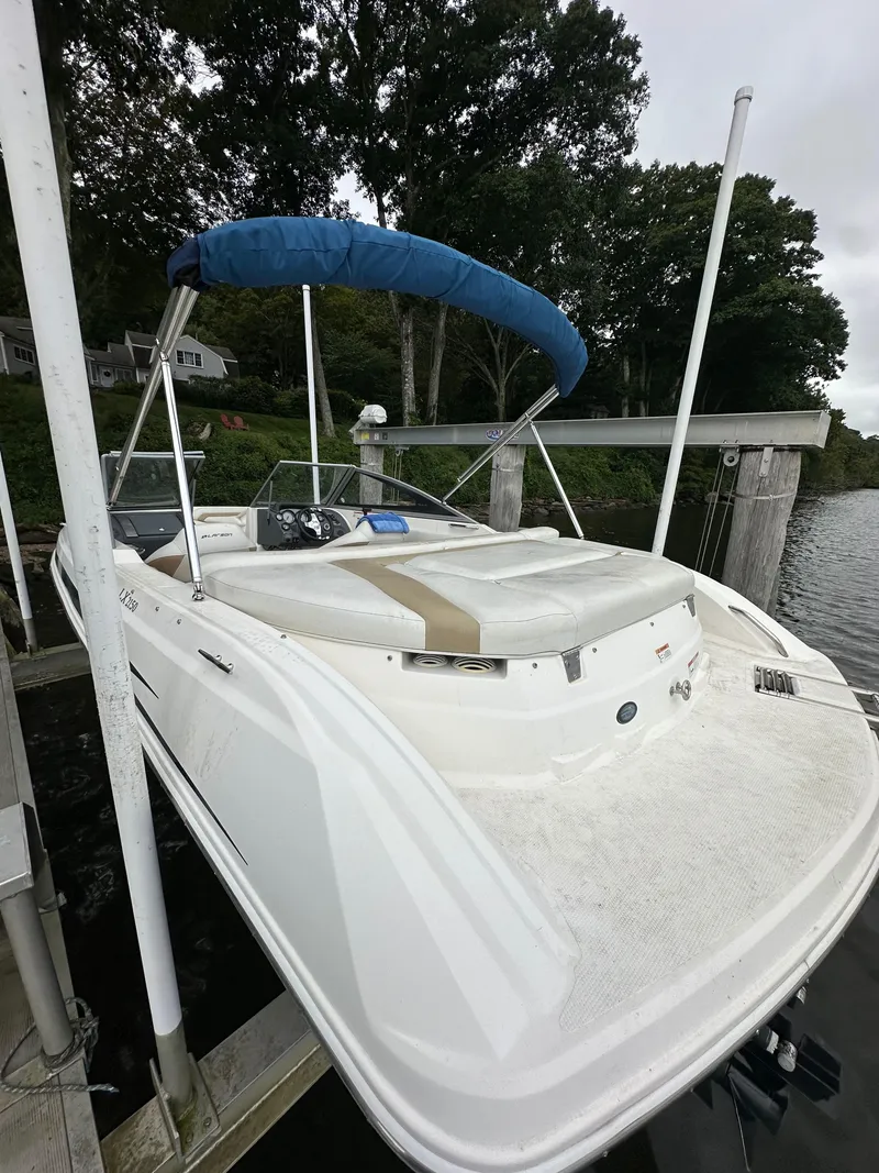 Slide: The Image of 2012 Chaparral 220 SSi boat docked with blue canopy, surrounded by trees. - 4