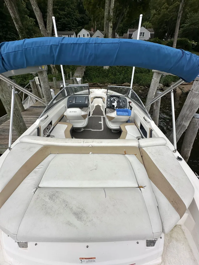 Slide: The Image of 2012 Chaparral 220 SSi boat with blue canopy docked by trees. - 5