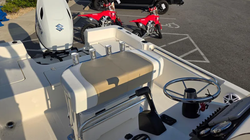 Slide: The Image of 2025 Bulls Bay 2000 boat interior with steering wheel and seating, parked near red motorcycles. - 8