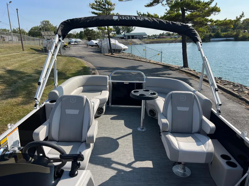 Slide: The Image of 2025 Godfrey Xperience 2286 SBX pontoon boat with spacious seating and canopy on a sunny day. - 10