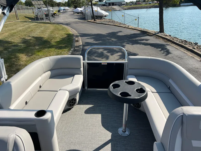 Slide: The Image of 2025 Godfrey Xperience 2286 SBX pontoon boat interior with seating and table by the water. - 12