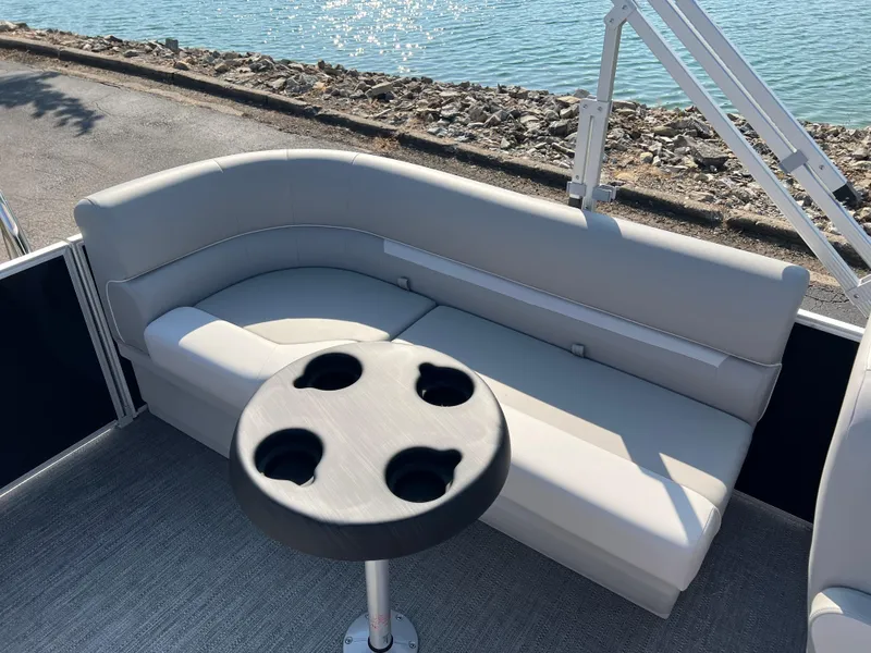 Slide: The Image of 2025 Godfrey Xperience 2286 SBX boat interior with gray seating and cup holder table. - 14
