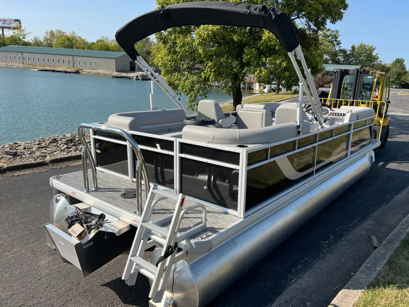 Slide: The Image of 2025 Godfrey Xperience 2286 SBX pontoon boat docked by a scenic waterfront. - 3