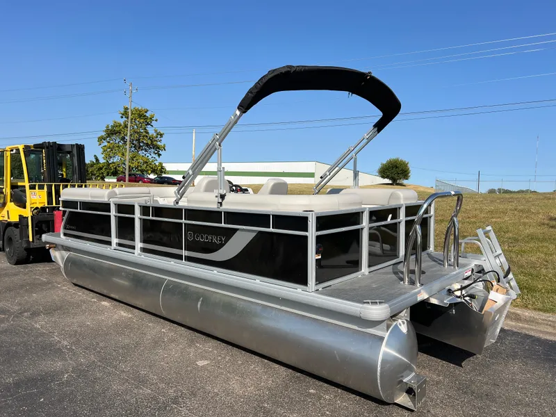 Slide: The Image of 2025 Godfrey Xperience 2286 SBX pontoon boat parked on pavement under clear blue sky. - 5