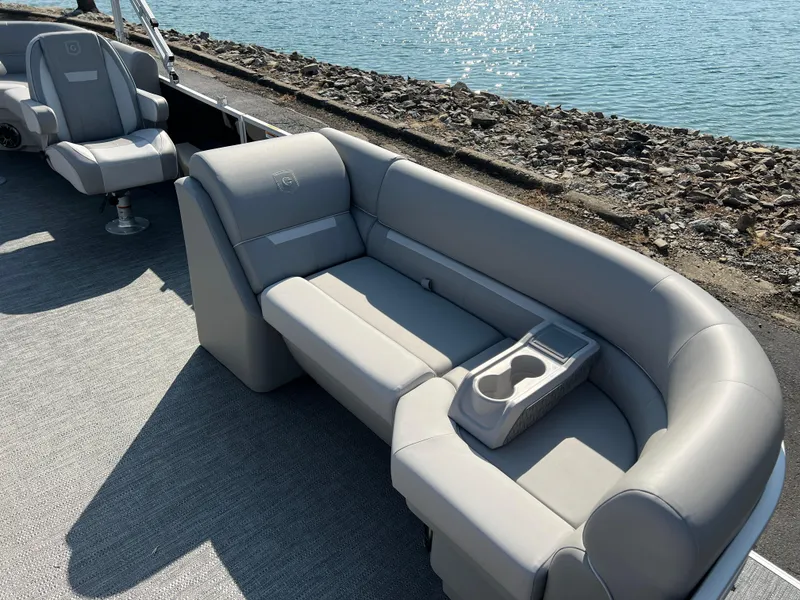 Slide: The Image of 2025 Godfrey Xperience 2286 SBX boat with gray seating and cup holders by the water. - 9