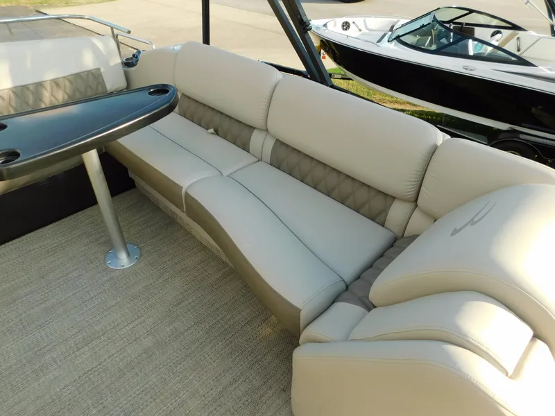 Slide: The Image of 2018 Bennington 25 R pontoon boat interior with beige seating and a black table. - 26