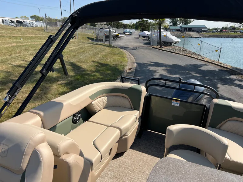 Slide: The Image of 2025 Godfrey SWEETWATER 2286 MT pontoon boat interior with beige seating near a lakeside dock. - 13
