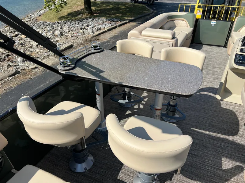 Slide: The Image of 2025 Godfrey SWEETWATER 2286 MT boat interior with seating and table, near water. - 18