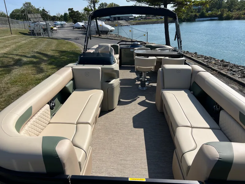 Slide: The Image of 2025 Godfrey SWEETWATER 2286 MT pontoon boat with spacious seating, docked by a serene lake. - 7