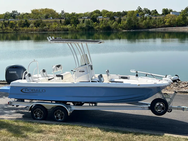 Slide: The Image of 2025 Robalo 206 Cayman boat on trailer by a serene lake. - 1