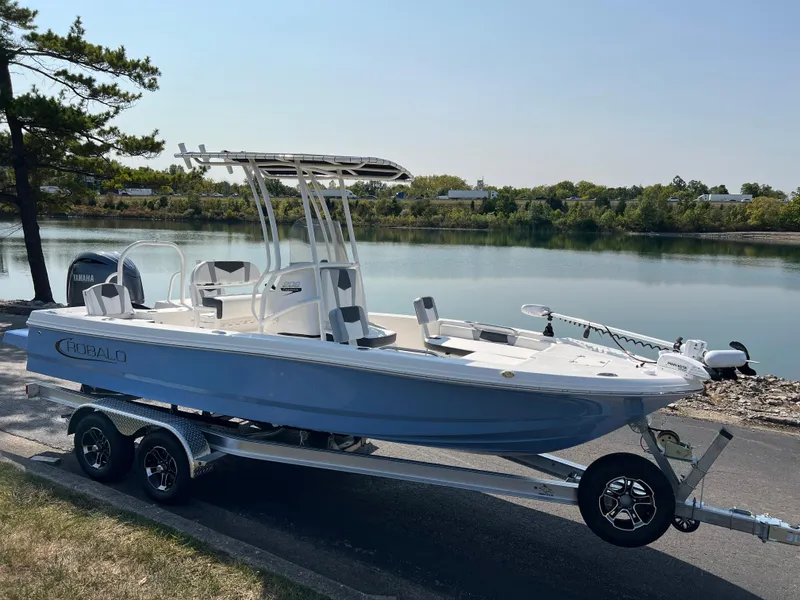 Slide: The Image of 2025 Robalo 206 Cayman boat on trailer by a serene lake. - 2