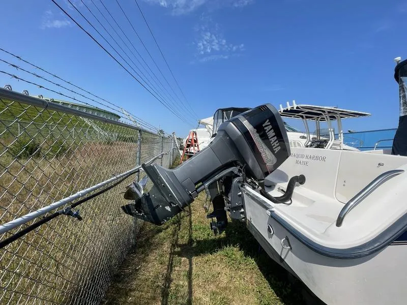 Slide: The Image of 1997 Grady-White 268 Islander boat with Yamaha outboard motor, parked near a chain-link fence. - 9