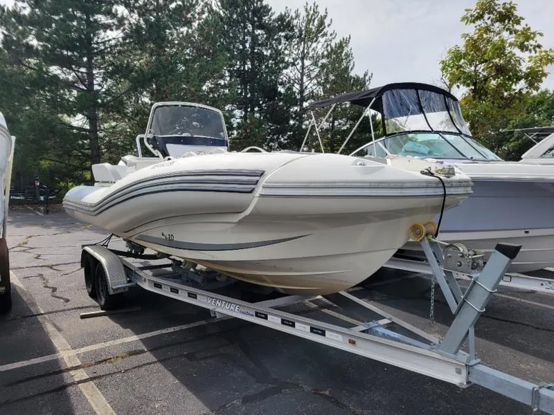 Slide: The Image of 2018 Zodiac NZO 22 boat on trailer in parking lot, surrounded by trees. - 10