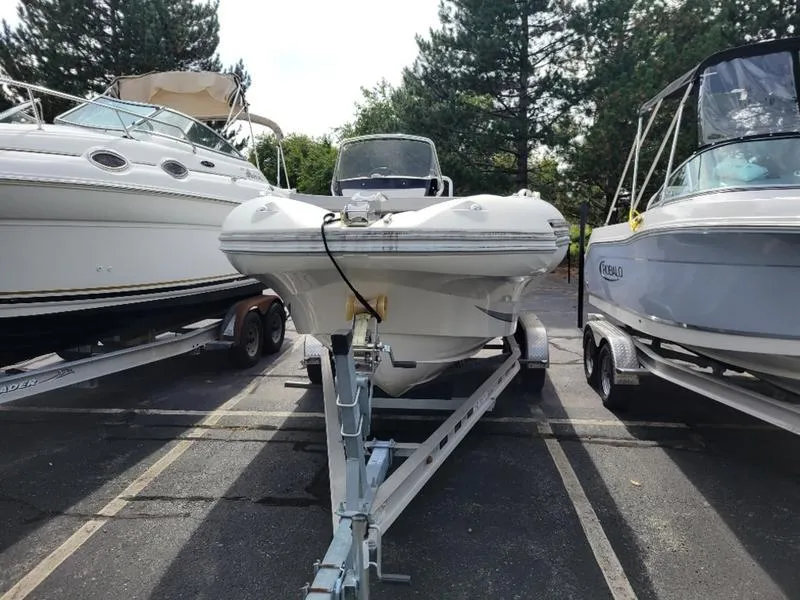 Slide: The Image of 2018 Zodiac NZO 22 boat on trailer, parked between two other boats. - 18