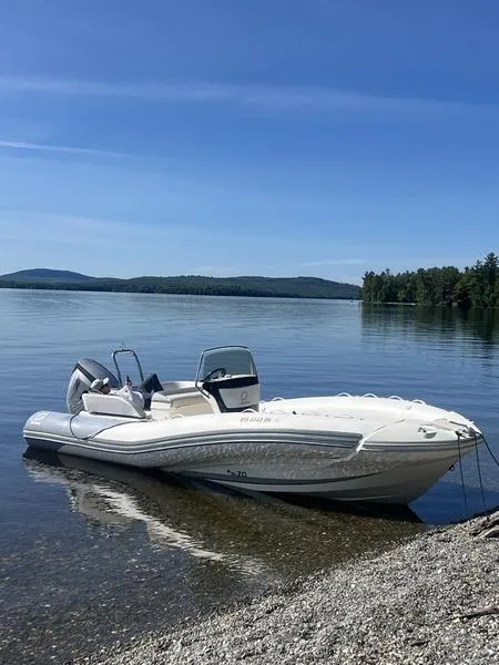 Slide: The Image of 2018 Zodiac NZO 22 boat on a serene lake shore under clear blue skies. - 8