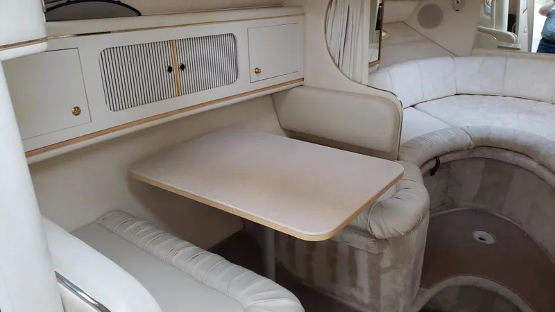 Slide: The Image of Interior of 2000 Sea Ray 290 Sundancer, featuring a cozy dining area with beige seating. - 7