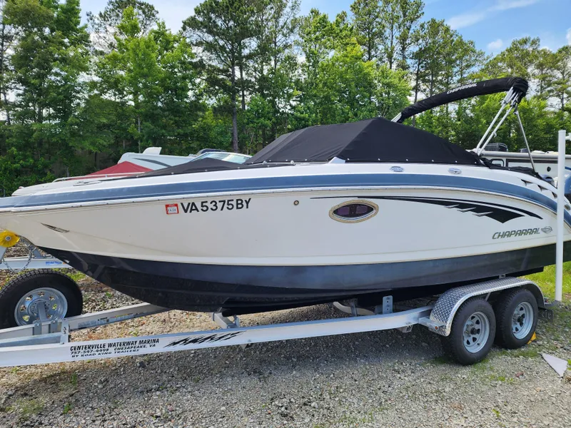 Slide: The Image of 2015 Chaparral 224 Sunesta boat on trailer, parked outdoors with trees in background. - 3