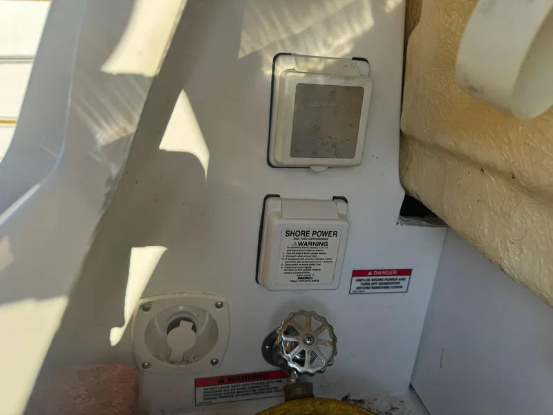 Slide: The Image of 2009 Sea Ray 240 Sundancer shore power connection and warning labels. - 17