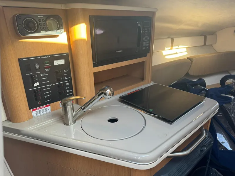 Slide: The Image of 2009 Sea Ray 240 Sundancer cabin kitchenette with sink, stove, and microwave. - 20