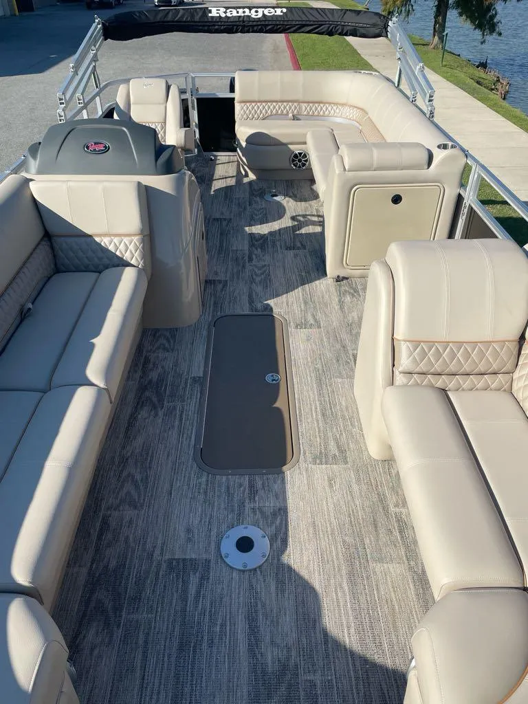 Slide: The Image of 2024 Ranger Reata 223C pontoon boat interior with beige seating and wood-style flooring. - 3