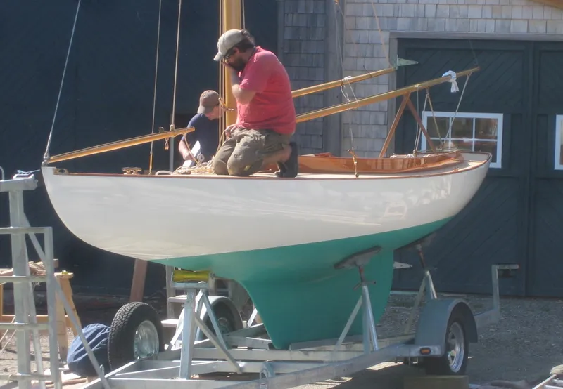 Slide: The Image of 2008 Herreshoff Full-Keel Buzzards Bay 15 sailboat on trailer, with two people working. - 10