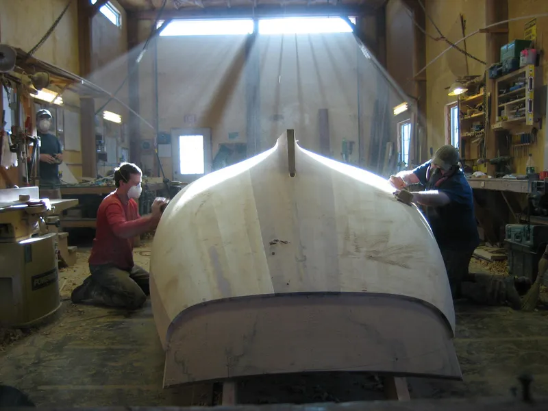 Slide: The Image of Craftsmen working on a 2008 Herreshoff Full-Keel Buzzards Bay 15 boat in a workshop. - 25