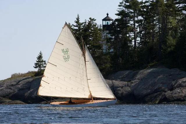 Slide: The Image of Sailboat Herreshoff Full-Keel Buzzards Bay 15 (2008) near rocky shore with lighthouse in background. - 5