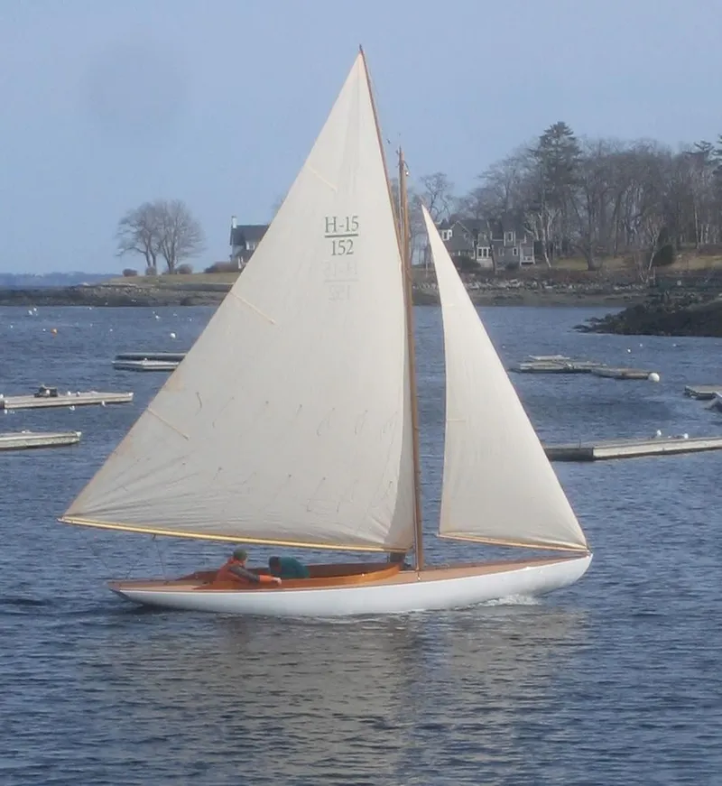 Slide: The Image of 2008 Herreshoff Full-Keel Buzzards Bay 15 sailboat on calm water, with scenic shoreline backdrop. - 6