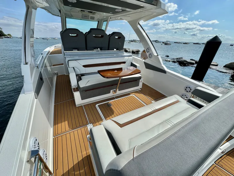 Slide: The Image of 2020 Tiara Sport 34 LS boat with luxurious seating and wooden deck, docked by the sea. - 10