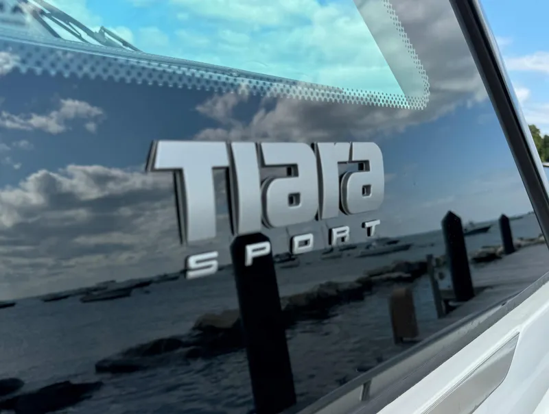 Slide: The Image of Tiara Sport 34 LS 2020 logo on boat window with scenic waterfront reflection. - 33