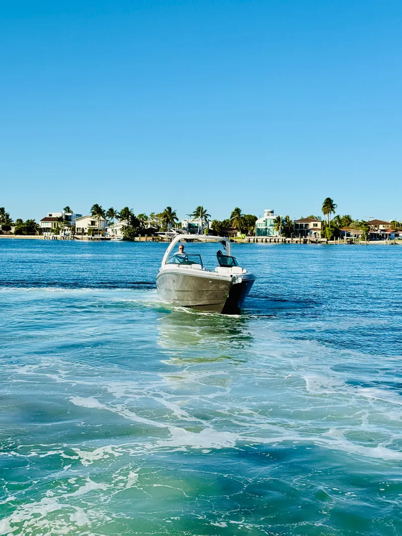 Slide: The Image of 2020 Monterey 328 SS boat cruising on a sunny day near coastal homes. - 13