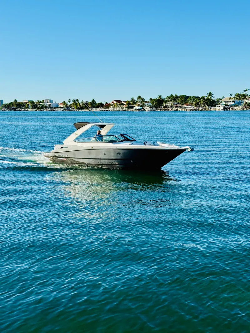 Slide: The Image of 2020 Monterey 328 SS boat cruising on clear blue water near a coastal shoreline. - 14