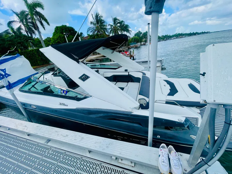 Slide: The Image of 2020 Monterey 328 SS boat docked by palm trees and water, with flag and shoes visible. - 21