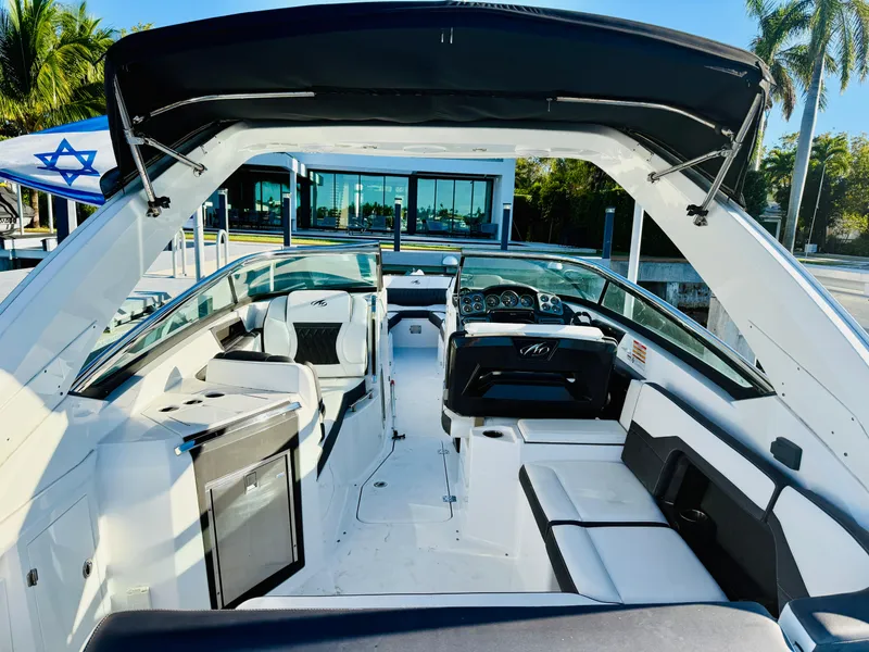 Slide: The Image of 2020 Monterey 328 SS boat interior with seating and dashboard, docked near a modern building. - 35