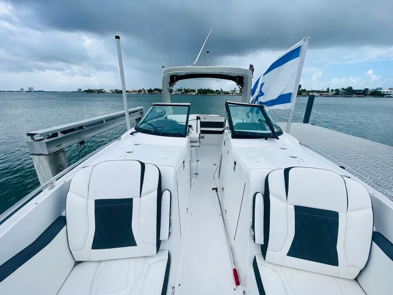 Slide: The Image of 2020 Monterey 328 SS boat docked, featuring sleek white seating and a flag. - 44