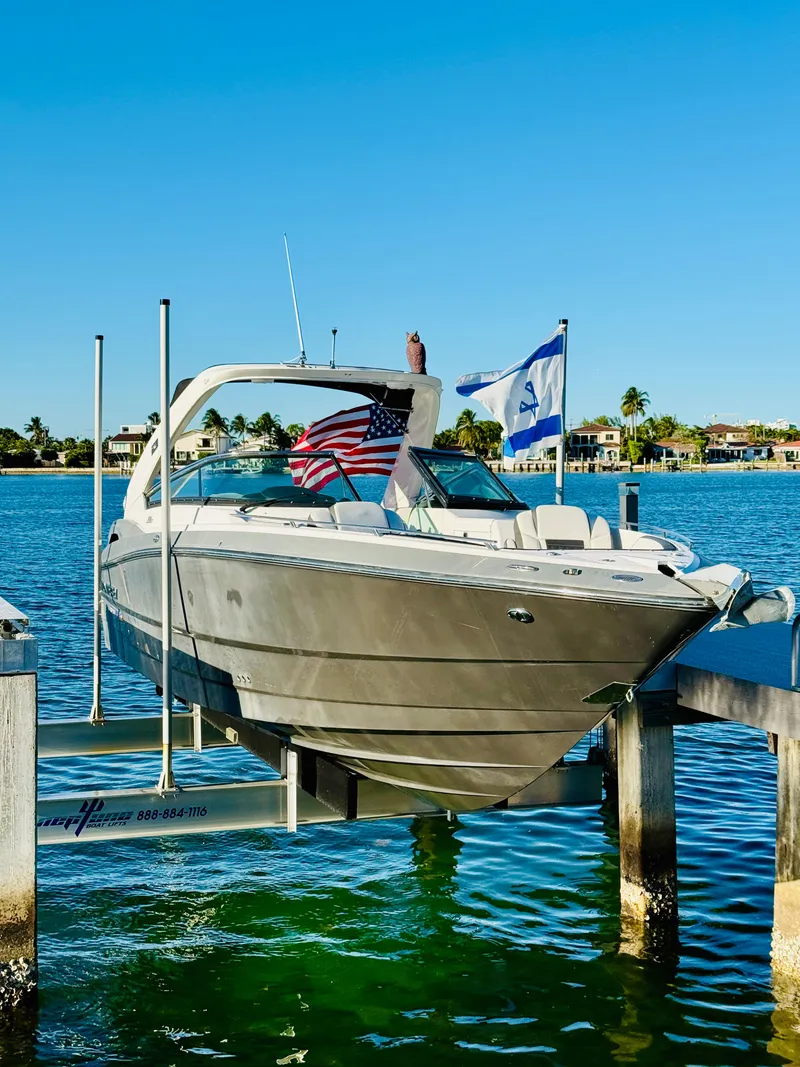 Slide: The Image of 2020 Monterey 328 SS boat docked with flags, clear blue sky, and waterfront homes. - 5