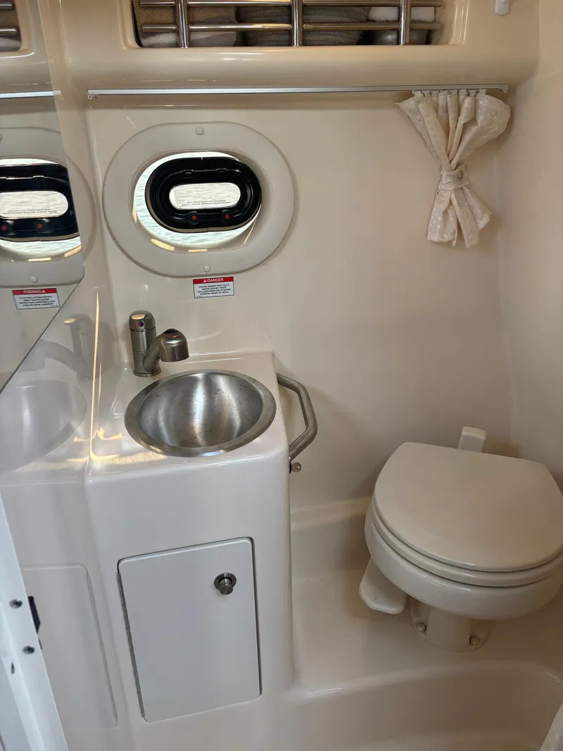 Slide: The Image of 2017 Sea Ray Sundancer 260 bathroom with sink, toilet, and porthole window. - 15