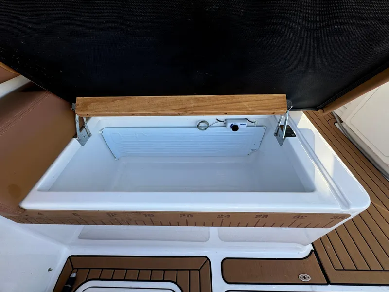 Slide: The Image of Open storage compartment on 2020 Southport 33 DC boat with wooden trim. - 12