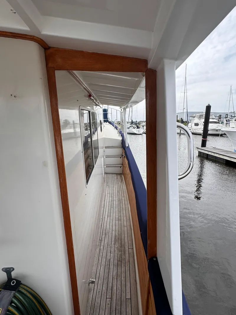 Slide: The Image of Side deck view of 1996 Kadey-Krogen 48 yacht at marina, featuring wooden trim and docked boats. - 17