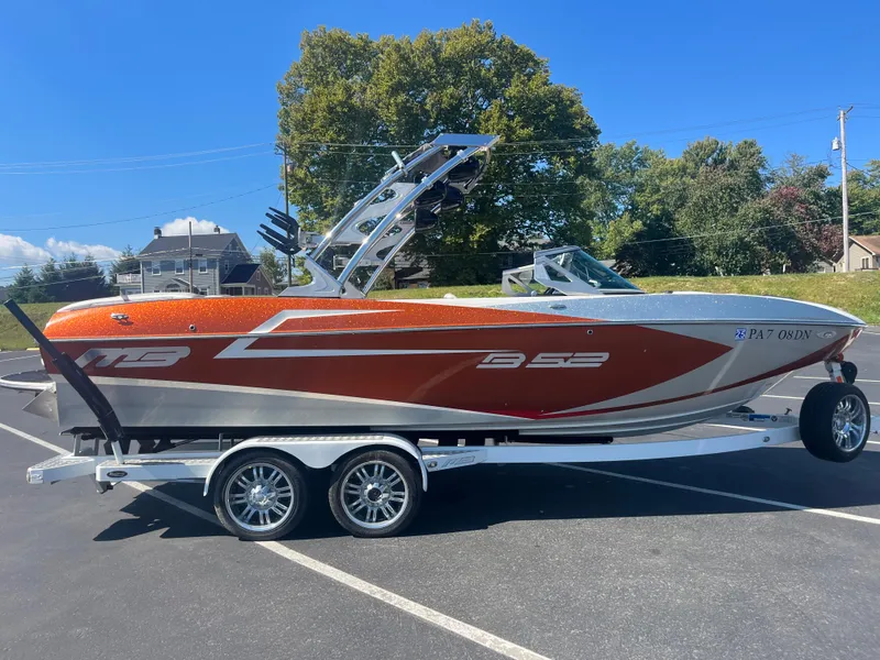 Slide: The Image of 2015 MB B52 23 boat on trailer, orange and silver, parked outdoors. - 4